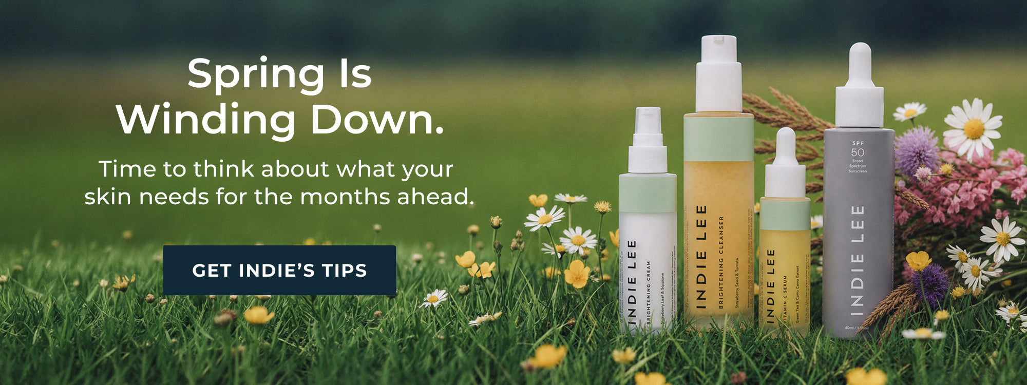 Indie Lee skincare products with flowers on grass, promoting tips for spring skin care.