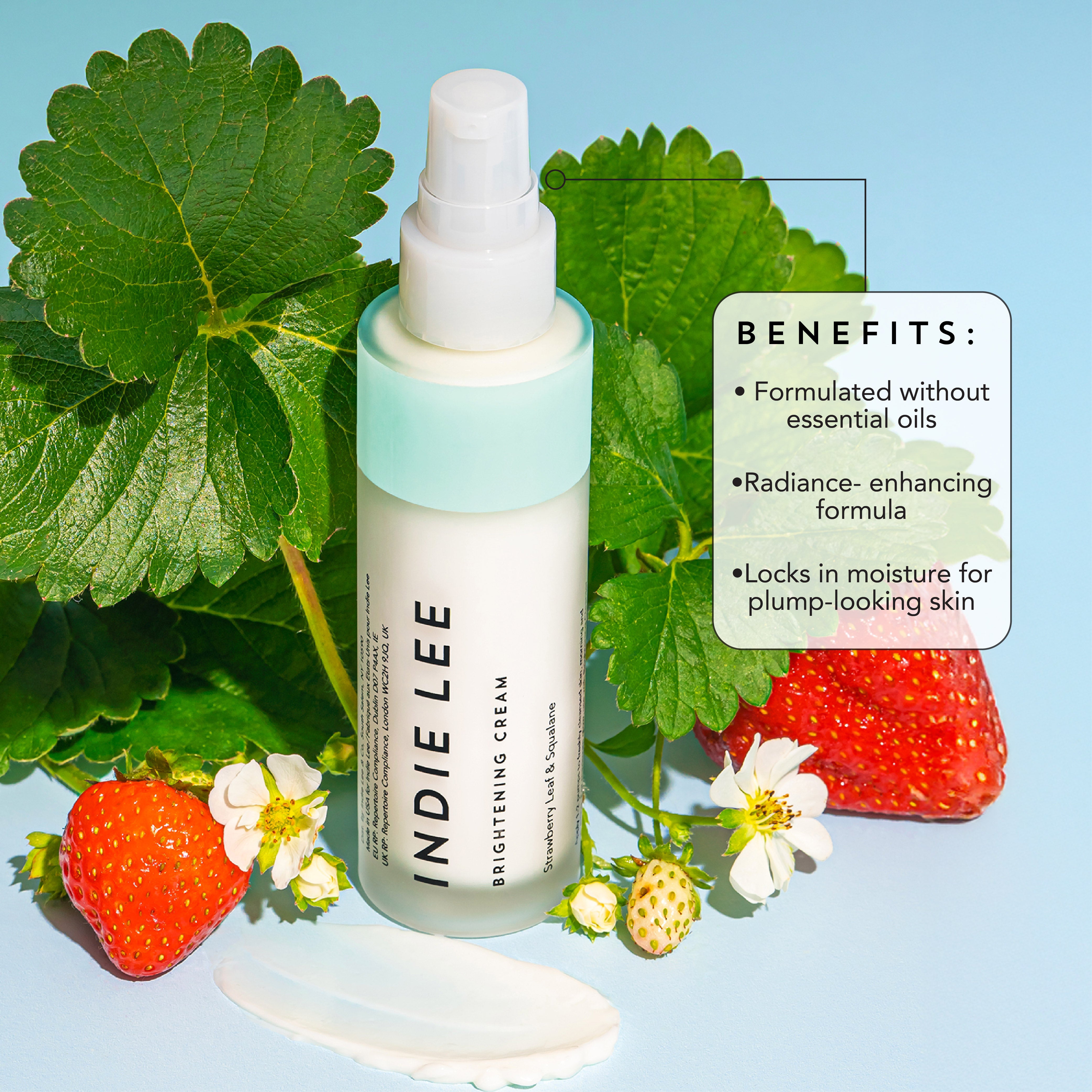 Indie Lee Brightening Cream bottle with strawberries and leaves on a light blue background