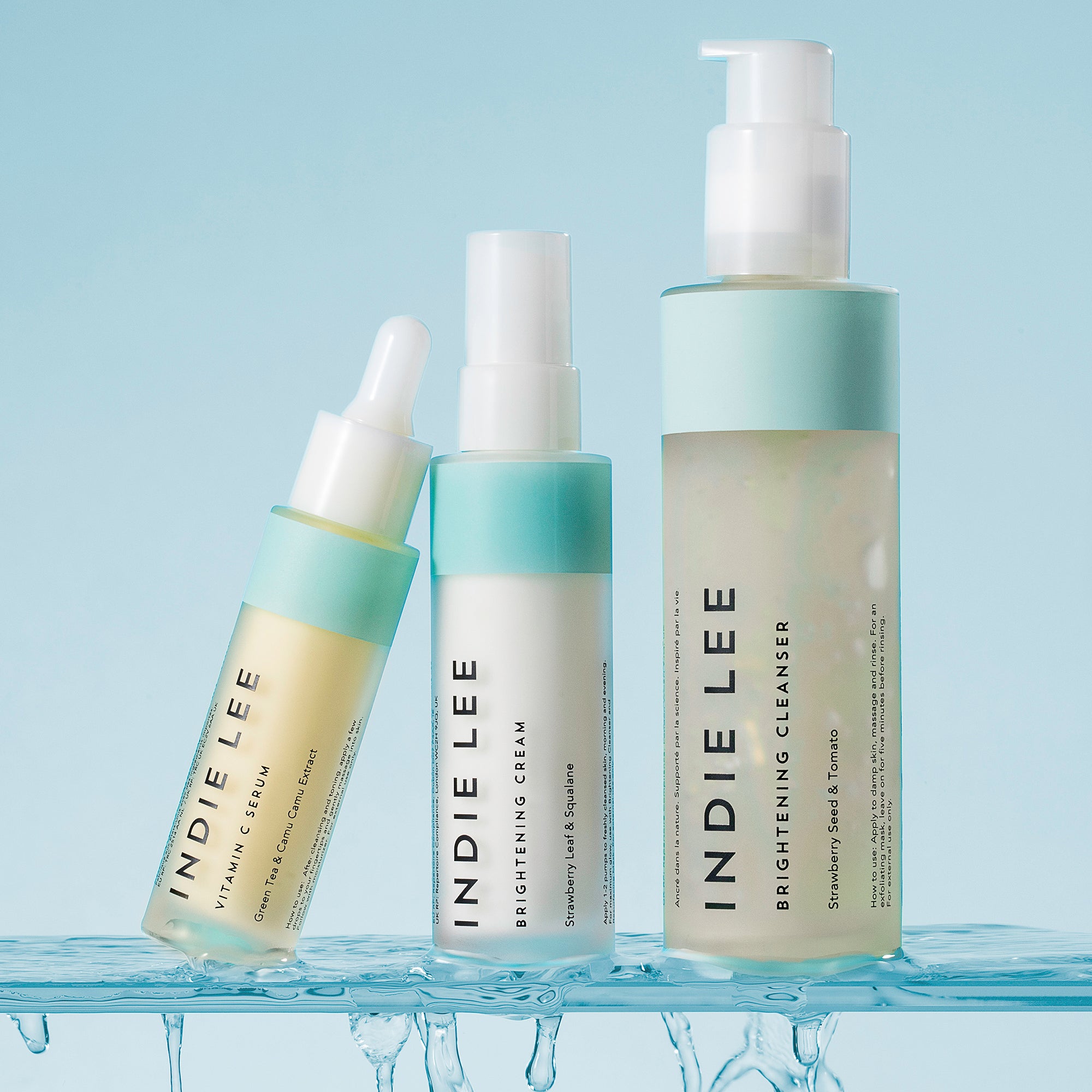 Three bottles of Indie Lee skincare on a light blue background