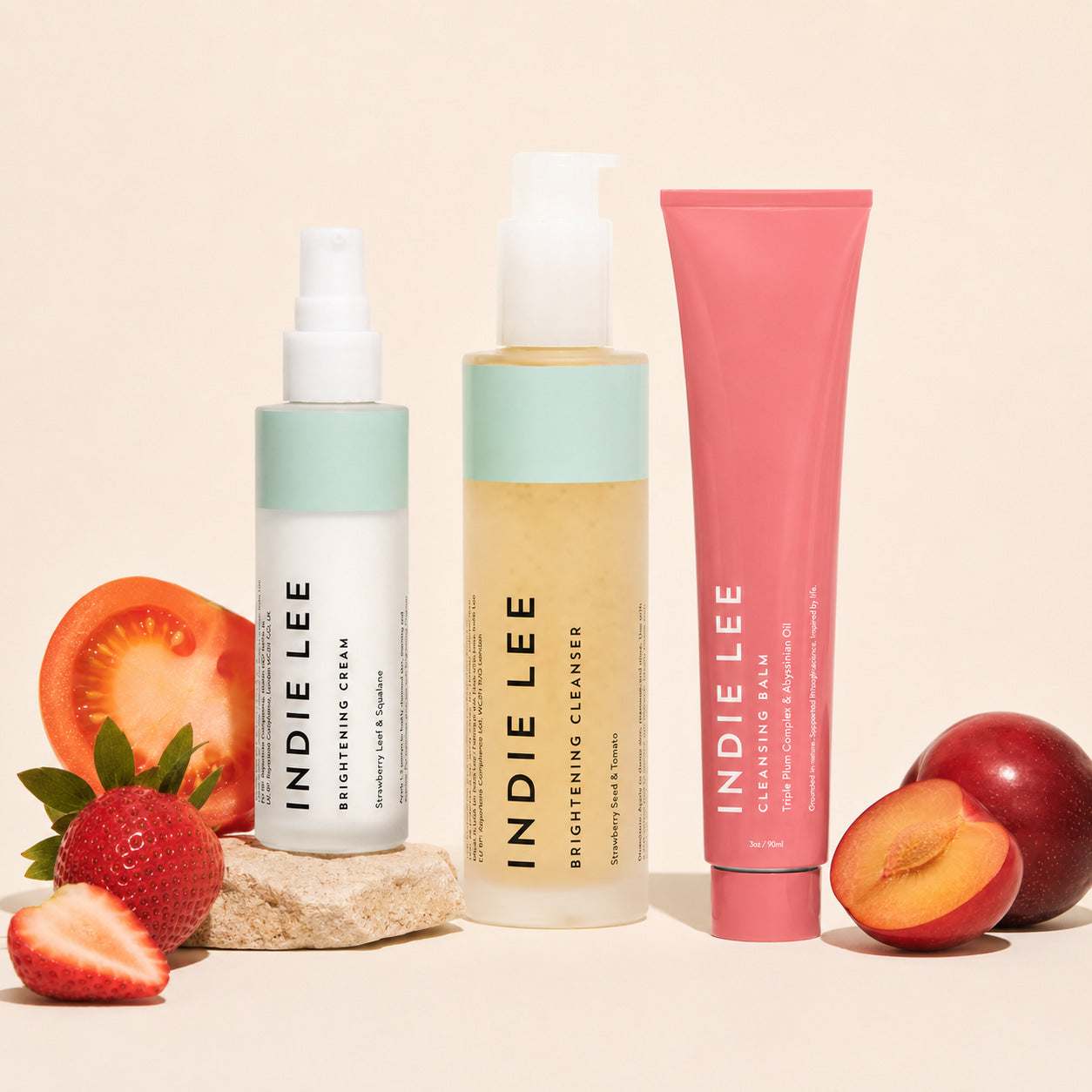 Indie Lee skincare products with fruits on a beige background