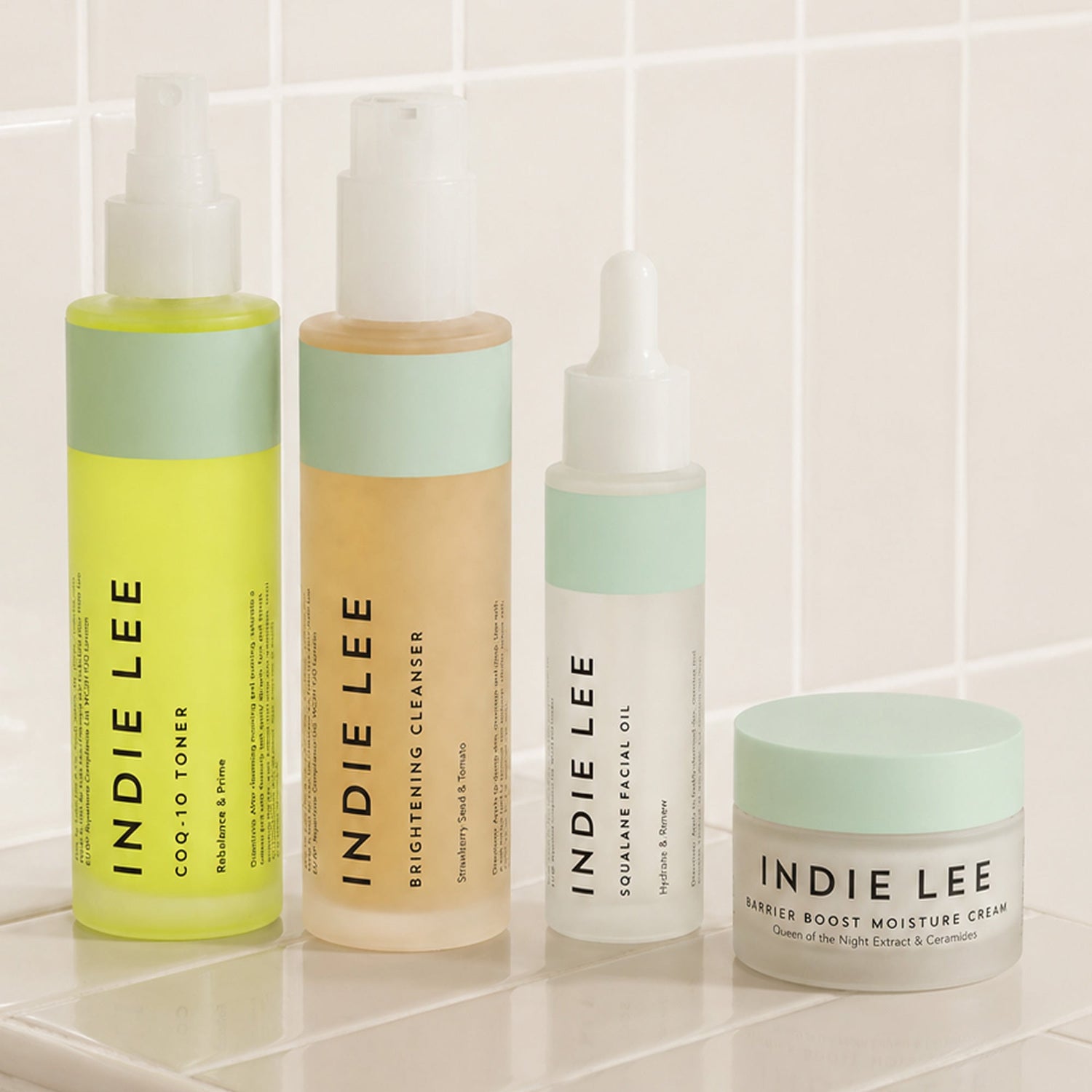 Indie Lee skincare products on a tiled surface