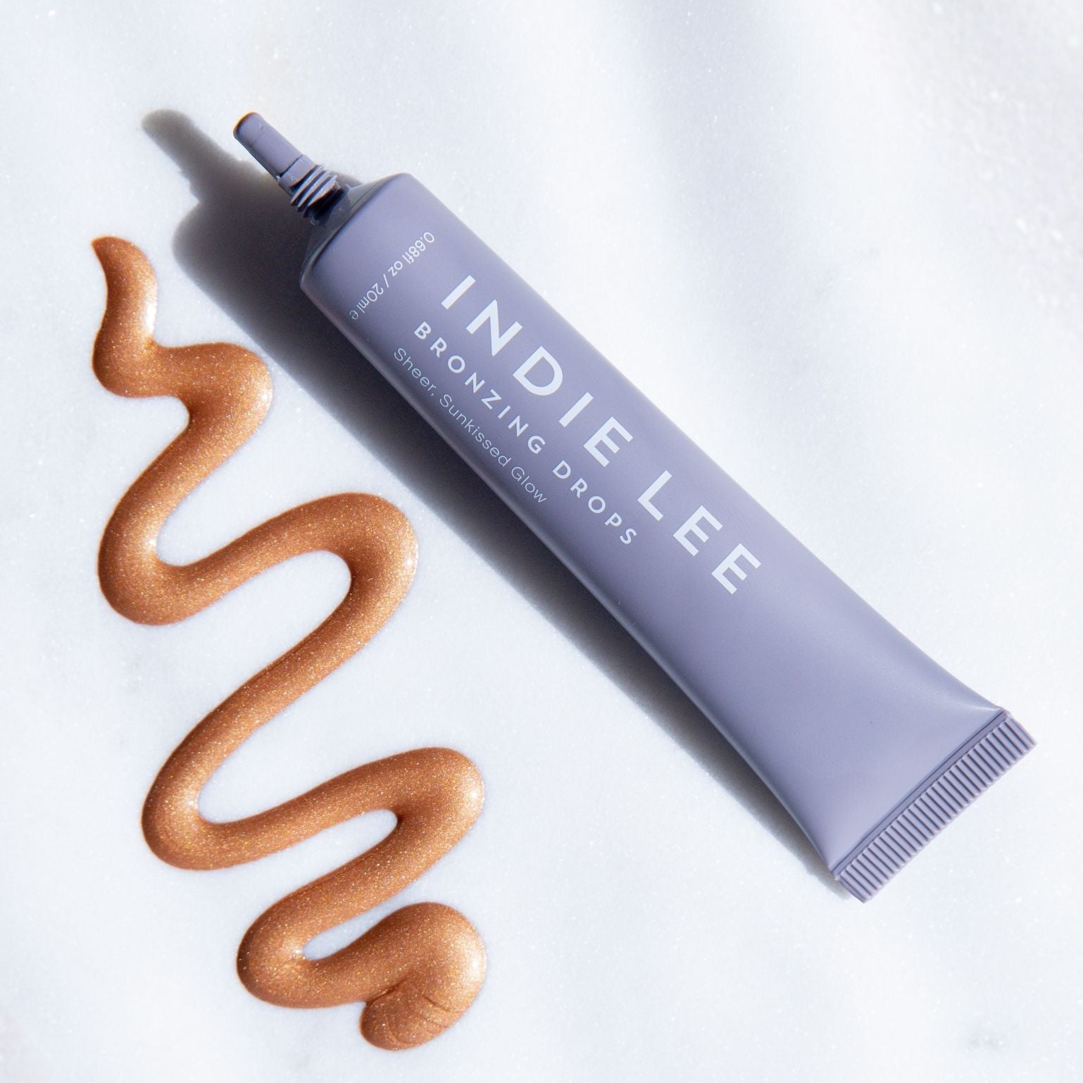 Indie Lee Bronzing Drops with swatch on a white background