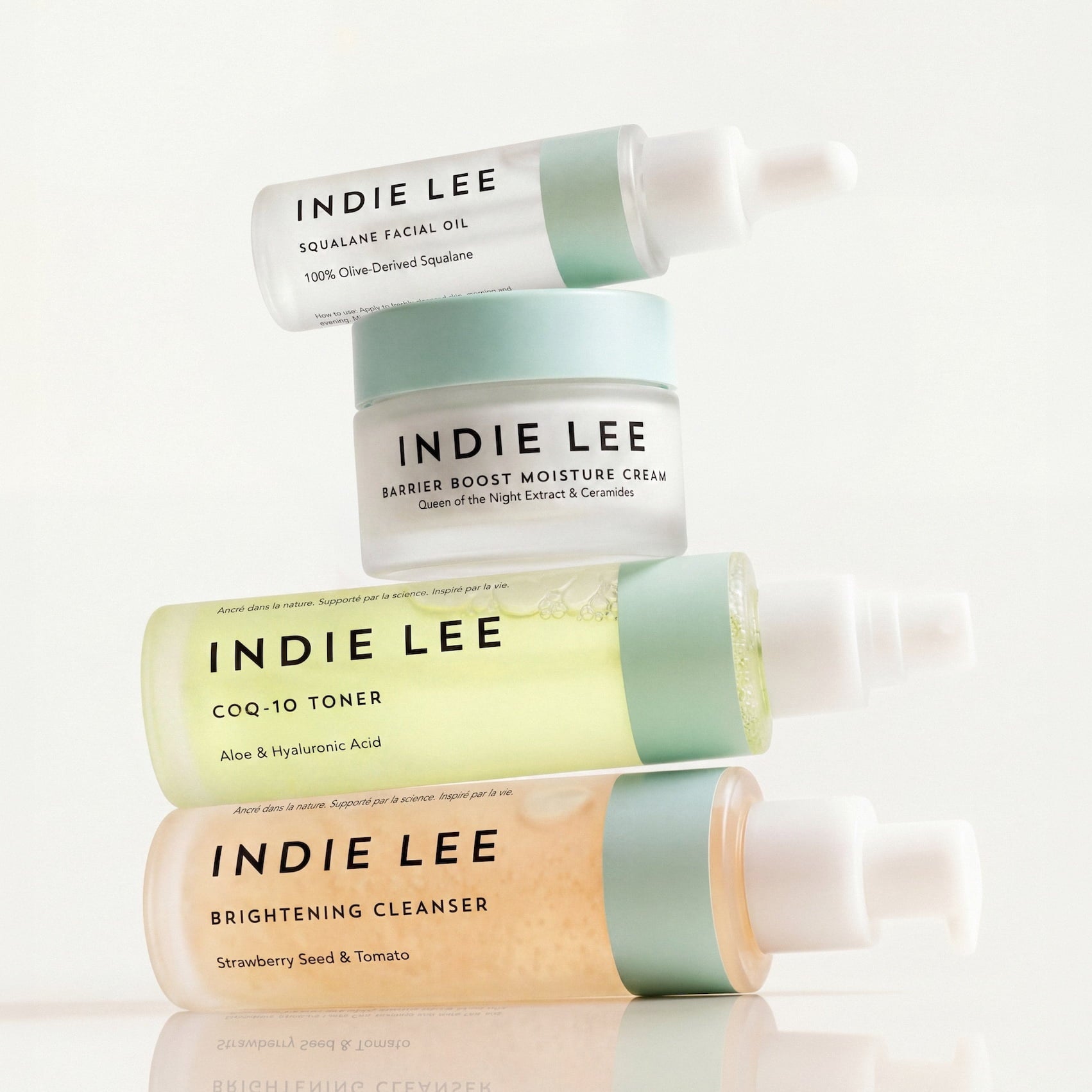 Four skincare products from Indie Lee stacked vertically on a clean white background.