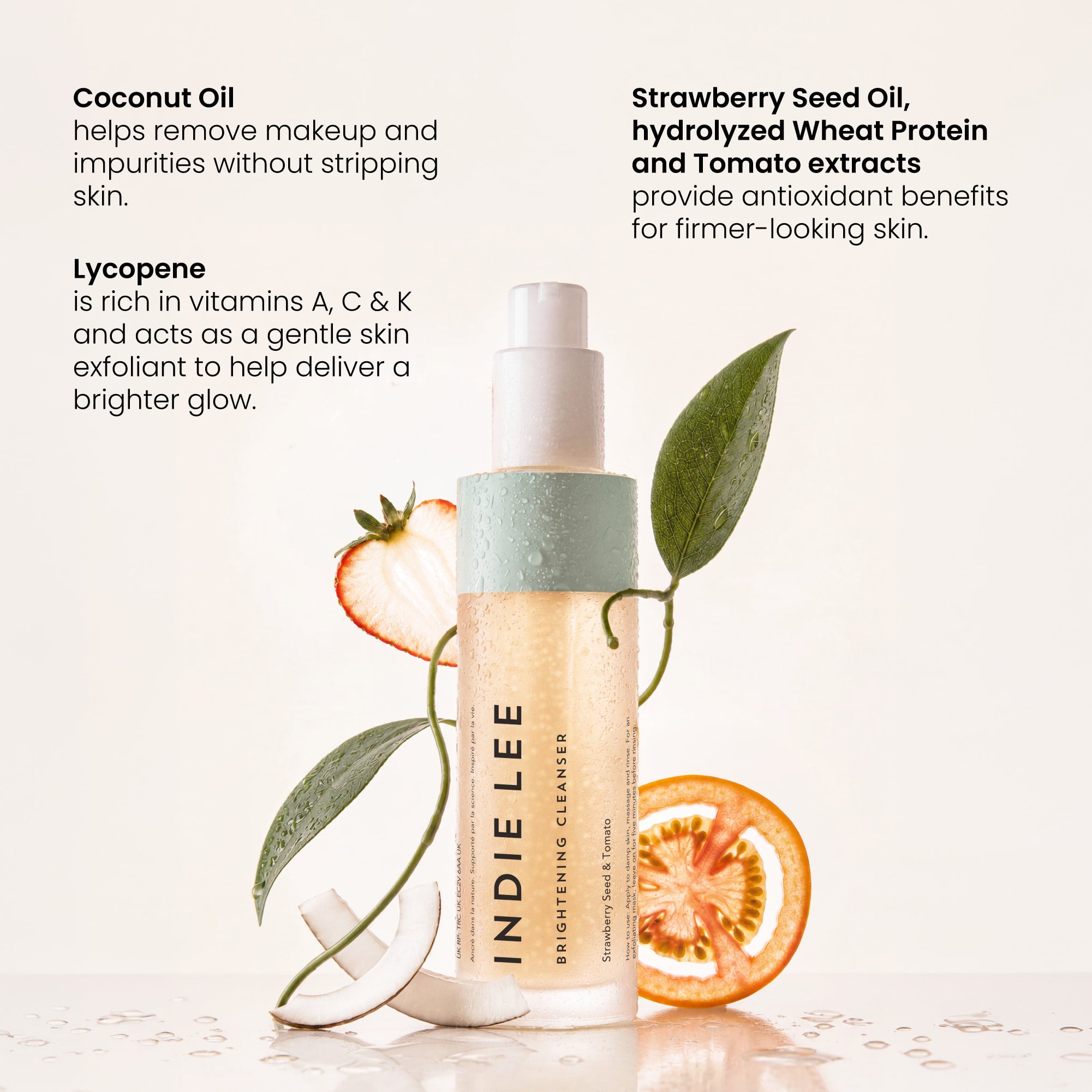 Indie Lee Brightening Cleanser bottle styled with fresh strawberry slices, a coconut half, and green leaves on a white background.