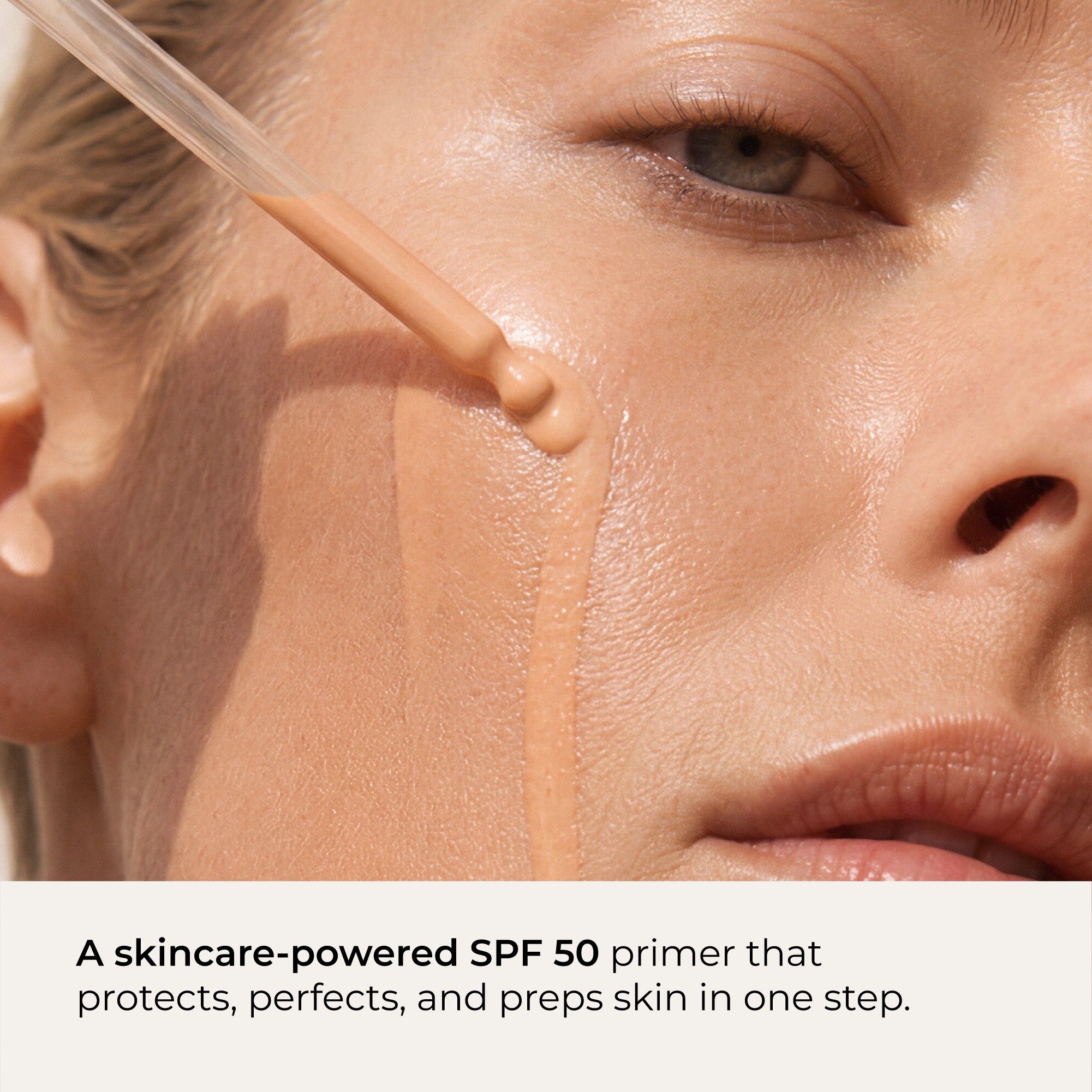 Close-up of a woman's face with an applicator dripping Indie Lee Daily SPF Primer onto her cheek with text overlay.